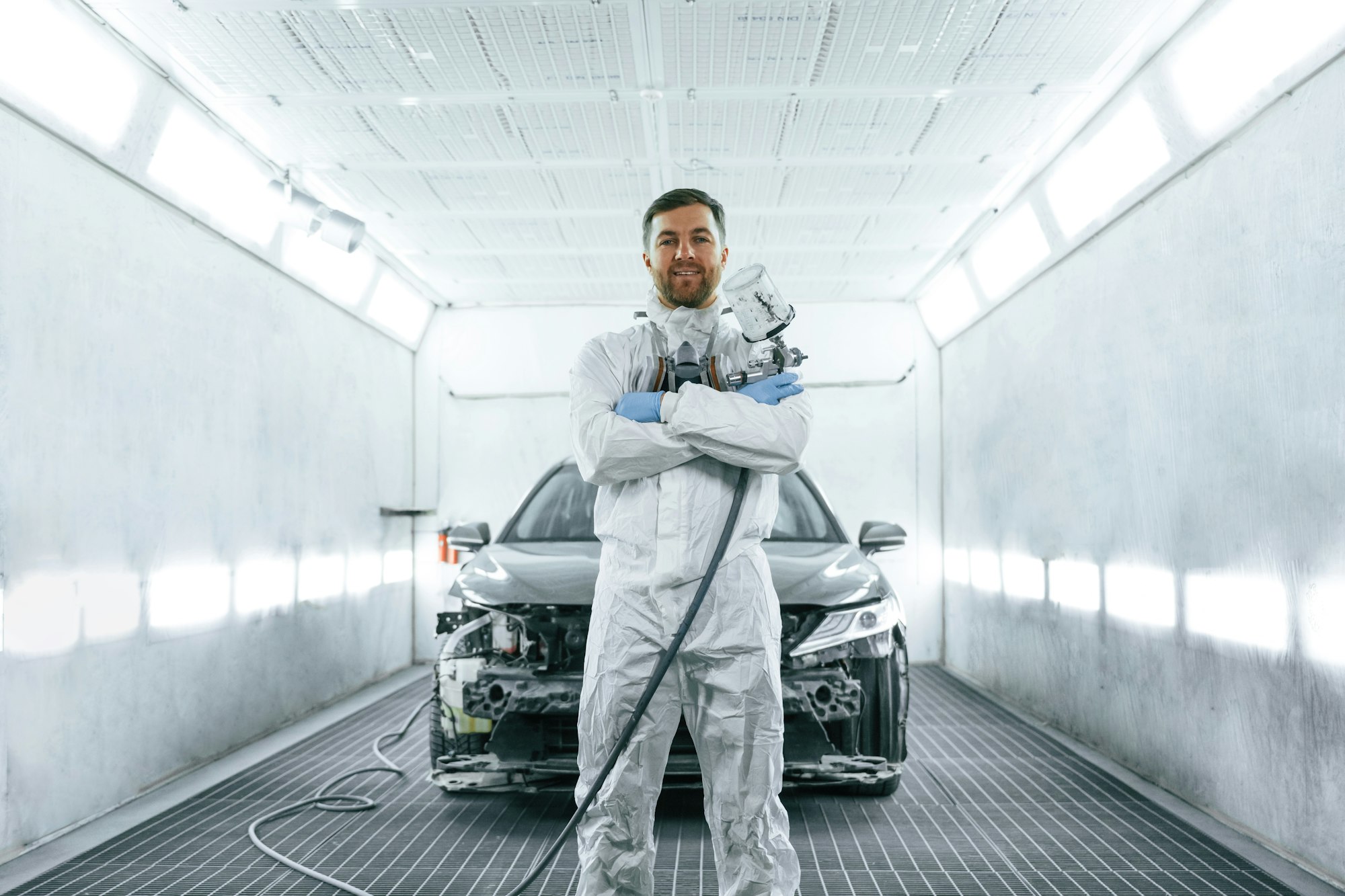 Man is standing and holding spray gun with paint for automobile